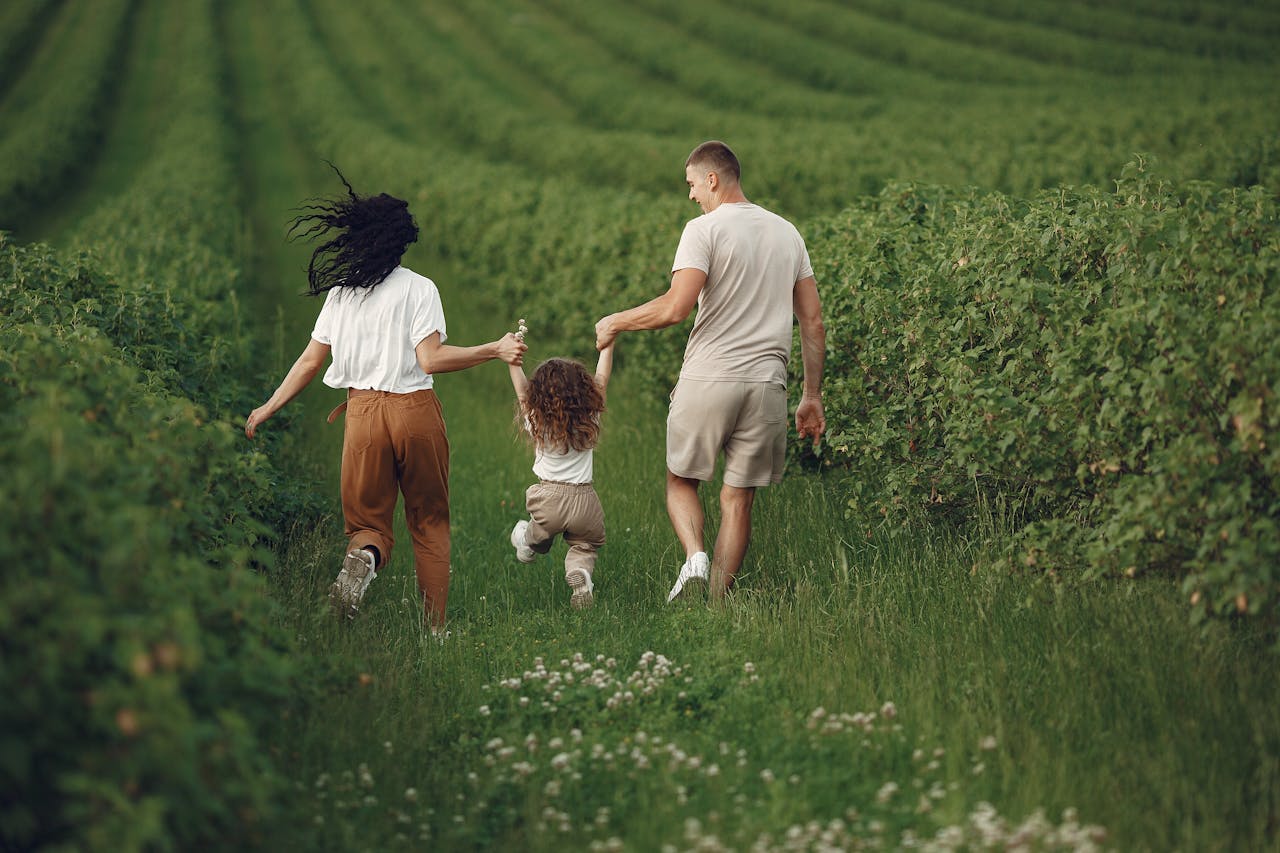 A joyful family strolls through a lush green field, enjoying quality time together.