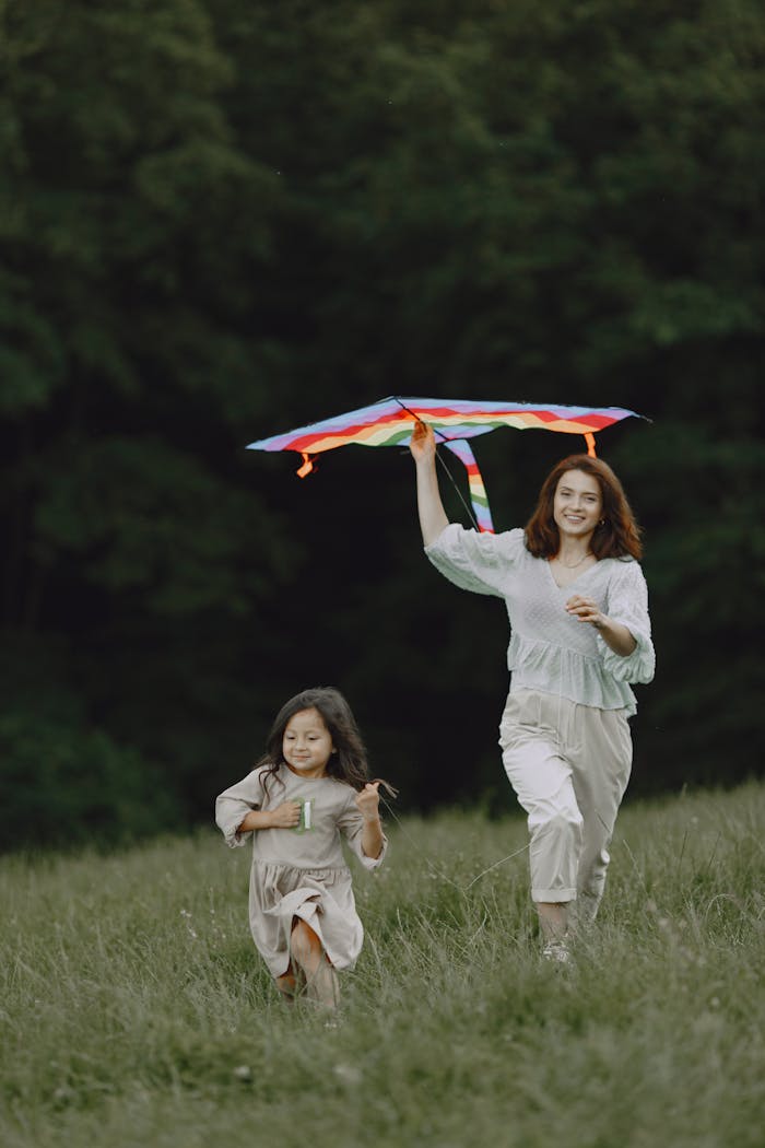 A joyful moment of a mother and daughter flying a kite on a sunny day outdoors.