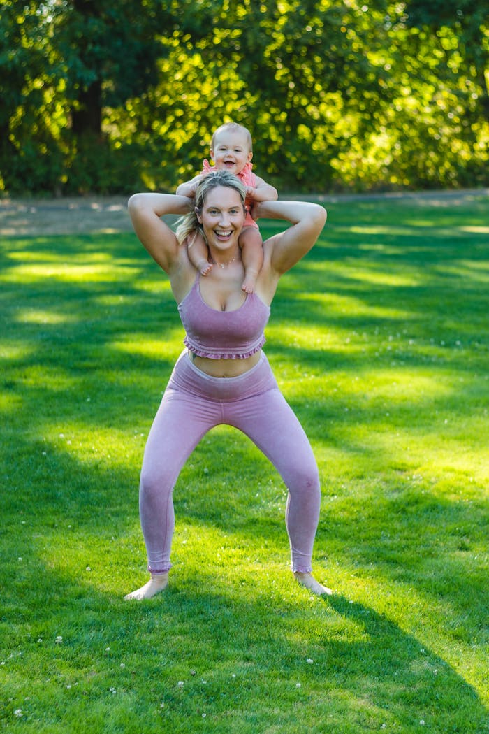 Mother and baby share fun moments outdoors, smiling joyfully on a sunny lawn.